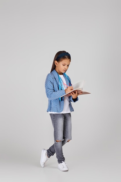 Cute little girl holding tape measure and notebook