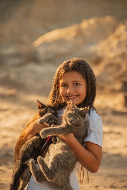 Милая маленькая девочка держит двух пушистых кошек