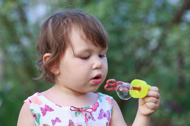 Cute little girl is blowing soap bubbles