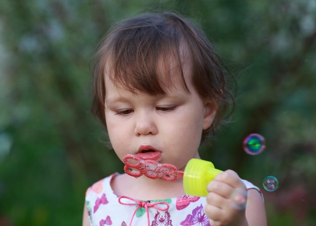 La bambina sveglia sta soffiando le bolle di sapone