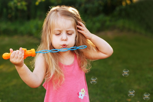 Cute little girl is blowing a soap bubbles