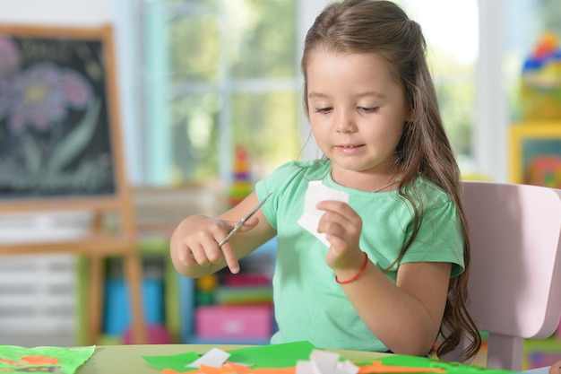 かわいい女の子は色紙を切っています小さな女の子は手工芸品を作ります