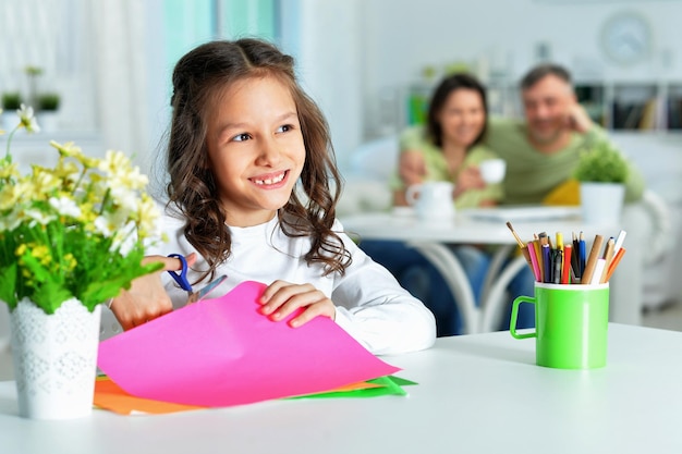 Cute little girl is cutting color paper