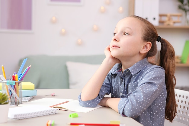 Cute little girl is doing homework in the interior of the room