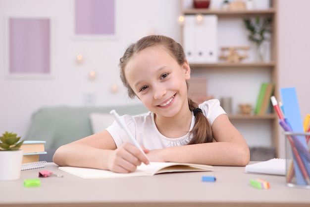 Cute little girl is doing homework in the interior of the room