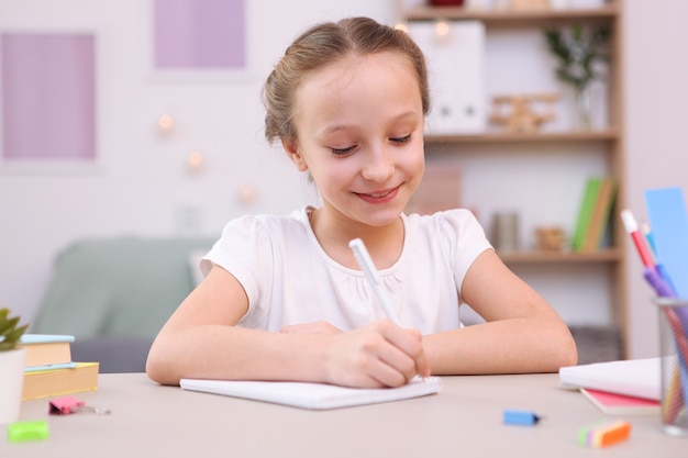 Cute little girl is doing homework in the interior of the room