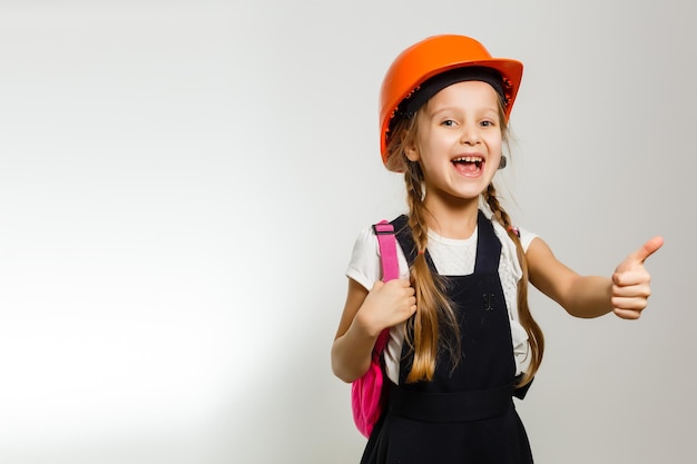 Cute little girl is isolated on white background. Girl looking at camera, wearing yellow helmet