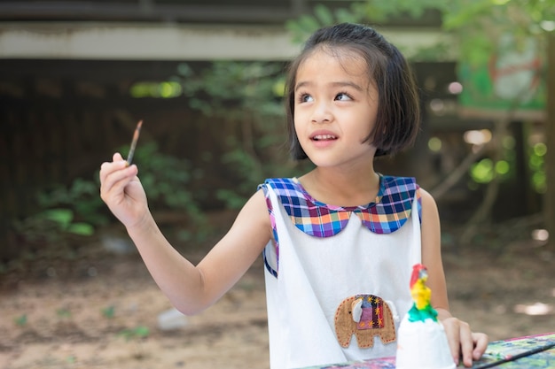 Foto la bambina sveglia sta imparando fuori dall'aula felicemente con una natura meravigliosa e un sorriso luminoso