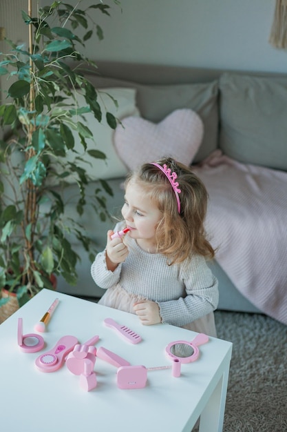 La bambina sveglia sta giocando in un salone di bellezza bella ragazza di 3 anni fa il trucco con i cosmetici per bambini a casa