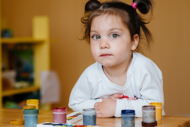 A cute little girl is playing and painting in her room. Recreation and entertainment.