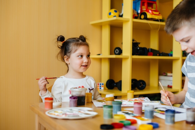 A cute little girl is playing and painting in her room. Recreation and entertainment.