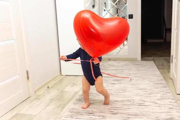 A cute little girl is playing with a red heartshaped ball Beautiful gift postcard