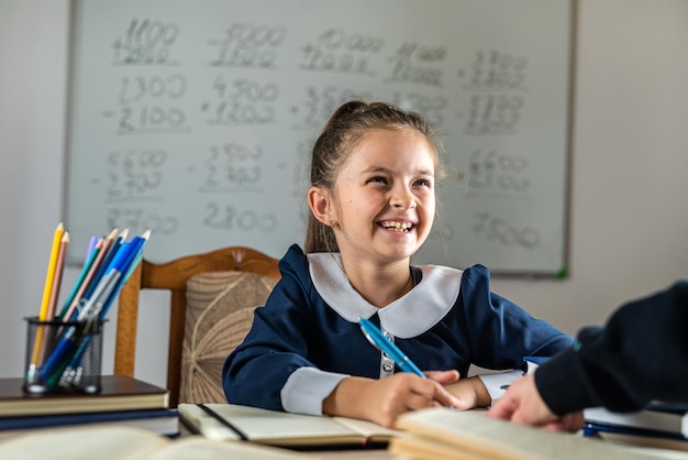 Cute little girl is pointed out by the teacher with his hand at her mistakes