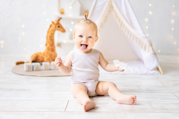 A cute little girl is sitting in a bright cozy children's playroom Textiles for children for the nursery A happy child