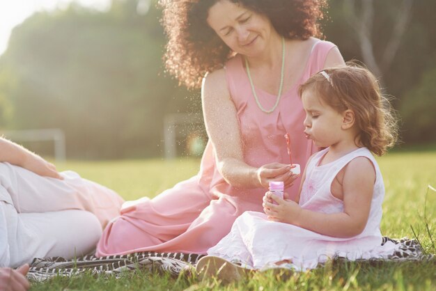 A cute little girl is spending time with her beloved grandfather and grandmather in the park. They had a picnic on the grass