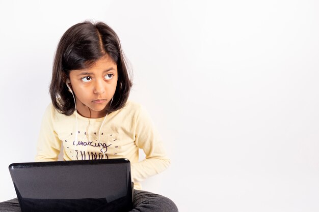 Photo cute little girl is using her notebook and headphones