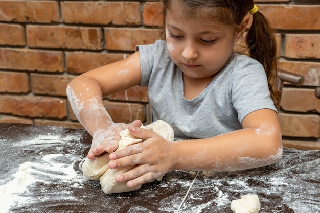 Bambina carina che impasta la pasta, prepara la pasta per la cottura