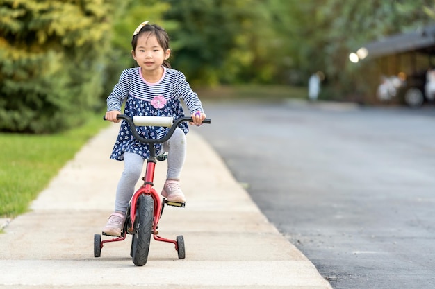 Cute little girl learning ride a bicycle with no helmet