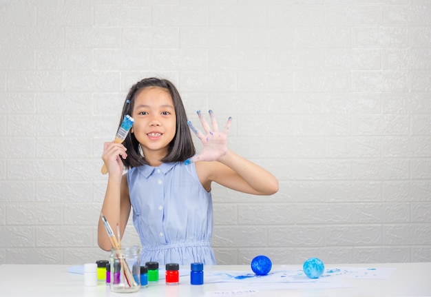 Cute little girl learning solar system making model with painting on foam ball