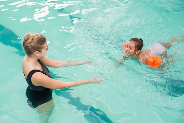 Симпатичная девочка учится плавать с тренером