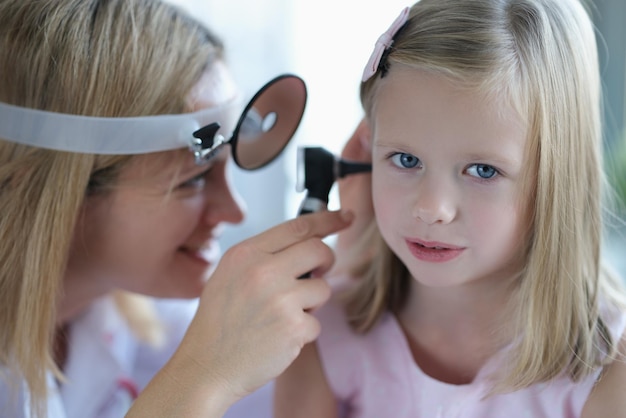 Cute little girl lets the doctor check ear closeup