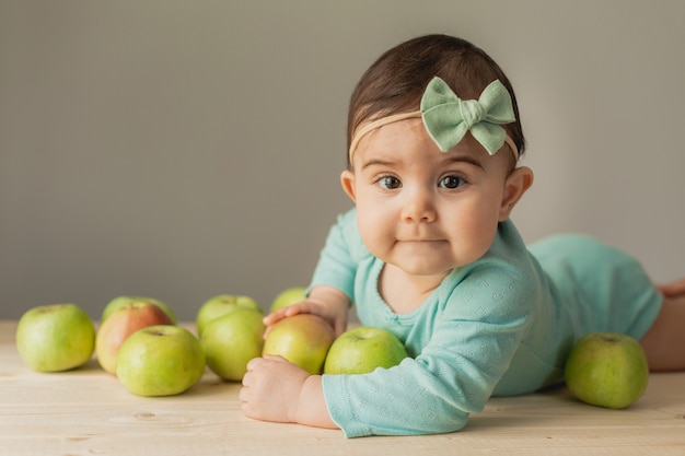 Cute little girl lies with green apples. eco-friendly products for children. High quality photo