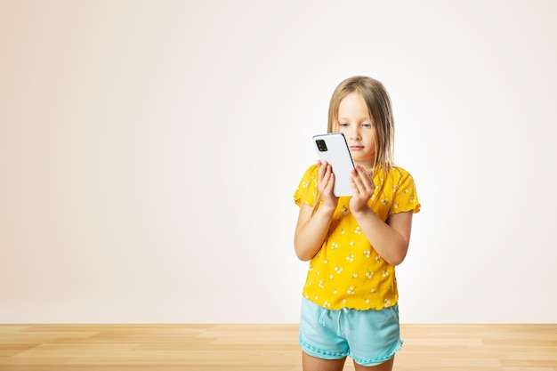 Cute little girl looks in smartphone Concept of chatting messaging with someone friends