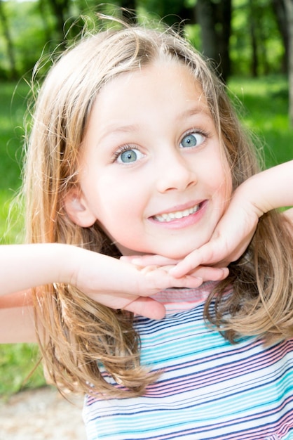 Cute little girl on the meadow in summer day with blue eyes