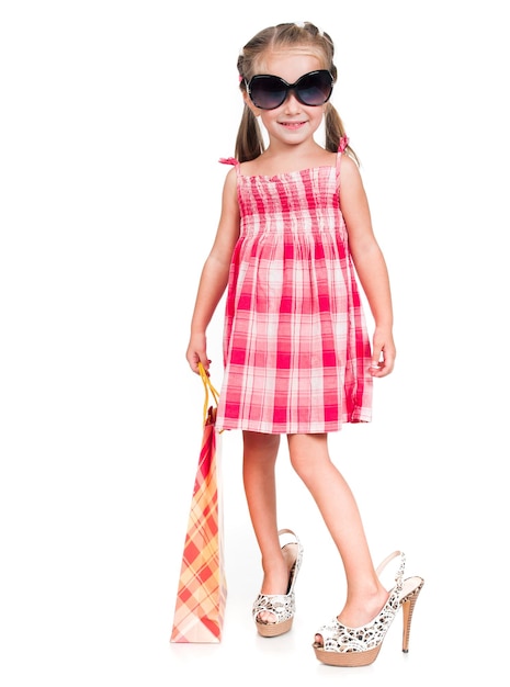 Cute little girl in mother glasses and shoes with shopping bag isolated on a white background