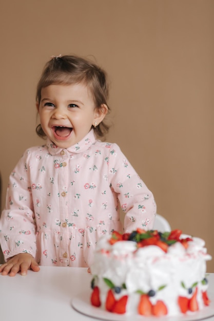 귀여운 소녀 한 살과 맛있는 생일 케이크 옆에 서 있는 18개월 된 소녀 베리 행복하고 웃는 채식 음식 유당과 글루텐 프리