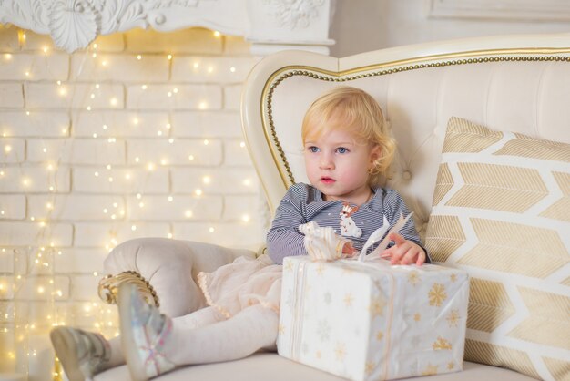 Photo cute little girl opens christmas presents