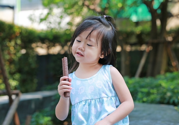 Cute little girl outside in nature eating chocolate bar