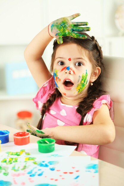 Cute little girl painting picture on home interior background