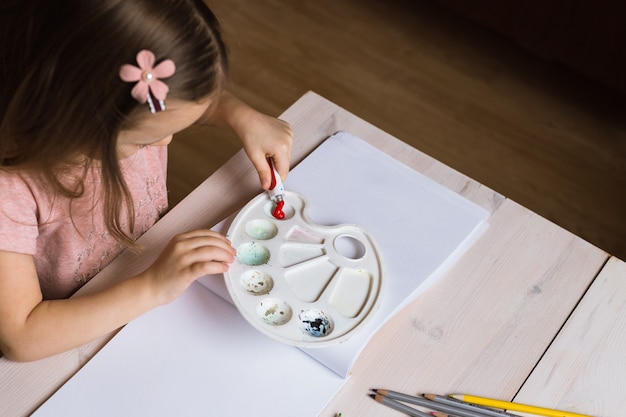 Cute little girl painting picture on home interior