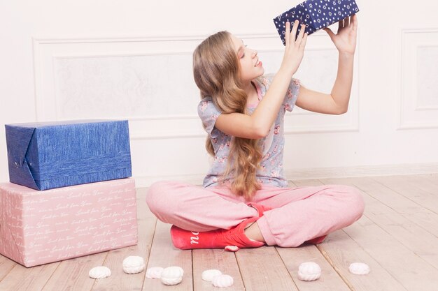 -床に座っているお菓子、幸せな子供時代のコンセプトを持つかわいい女の子のパジャマ。