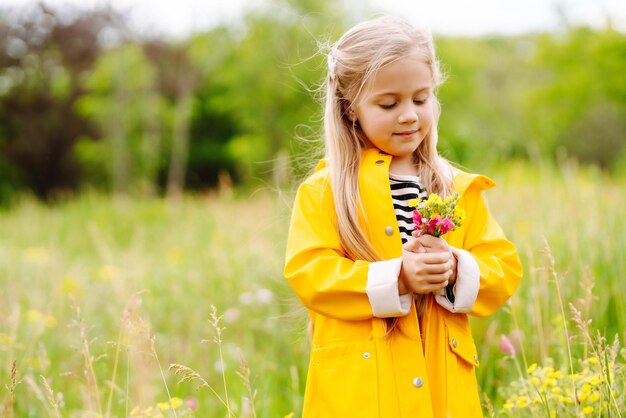 牧草地で野生の花を摘むかわいい女の子 子供が自然を探索する