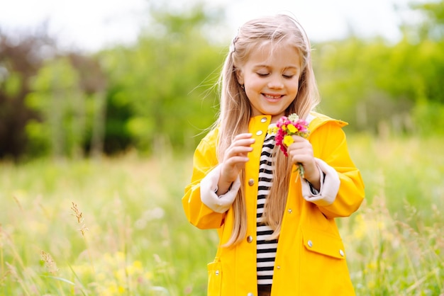 牧草地で野生の花を摘むかわいい女の子 子供が自然を探索する