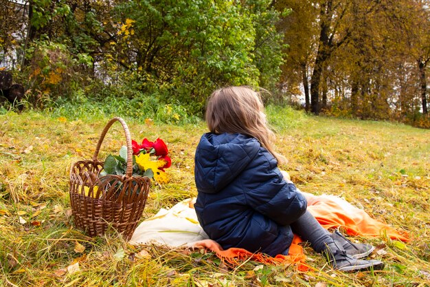 Cute little girl on a picnic in the autumn Park with a basket of roses