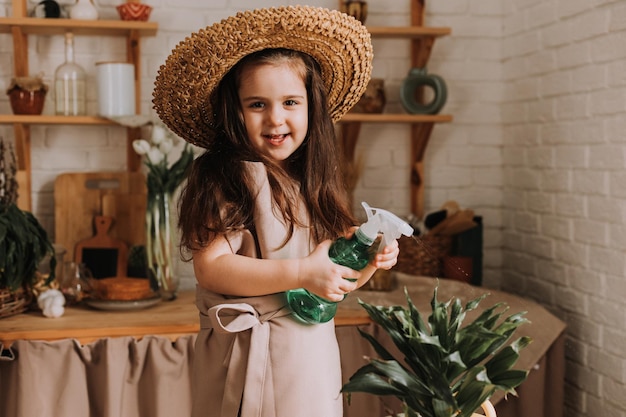 A cute little girl plants and waters a flower in a pot at home A little summer resident takes care of home flowers Earth Day