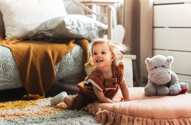 Cute little girl play in living room with stuffed animal toy feels excited moving have fun Playtime carefree child