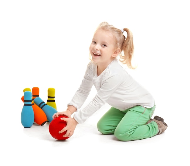 Cute little girl playing bowling on white background