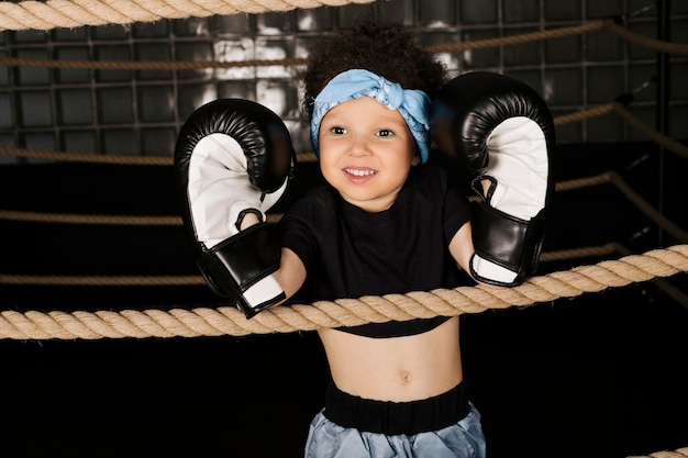 Cute little girl playing in the boxing ring wearing boxing gloves