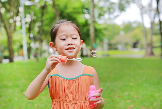 かわいい女の子が公園でバブルを遊んでいます。