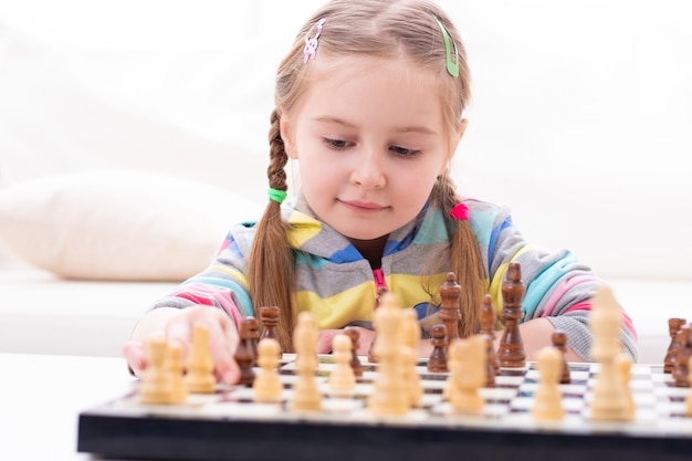 Cute little girl playing chess at home