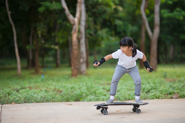 Милая маленькая девочка играет на скейтборде или серфинге в скейт-парке