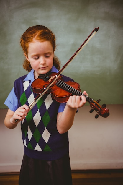 Cute little girl playing violin in classroom