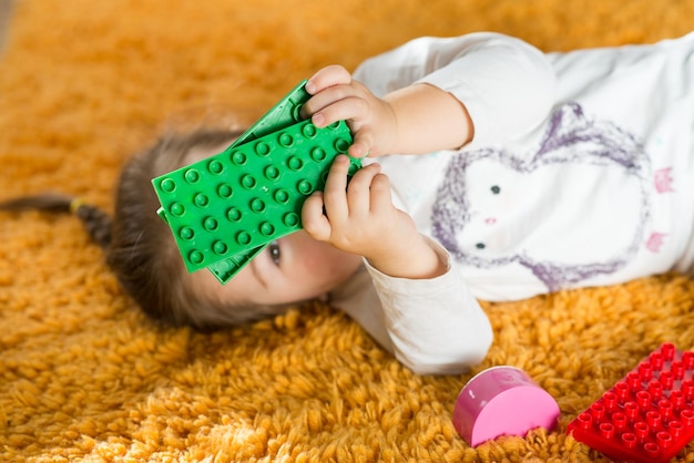 Cute little girl playing with colored blocks at home