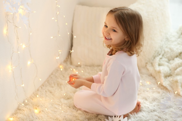Cute little girl playing with garland at home