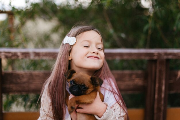 Foto bambina sveglia che gioca con il piccolo cane marrone