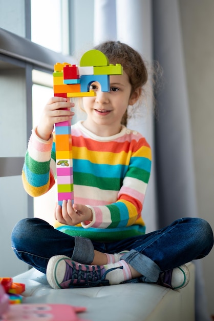 Photo a cute little girl plays construction set childhood development